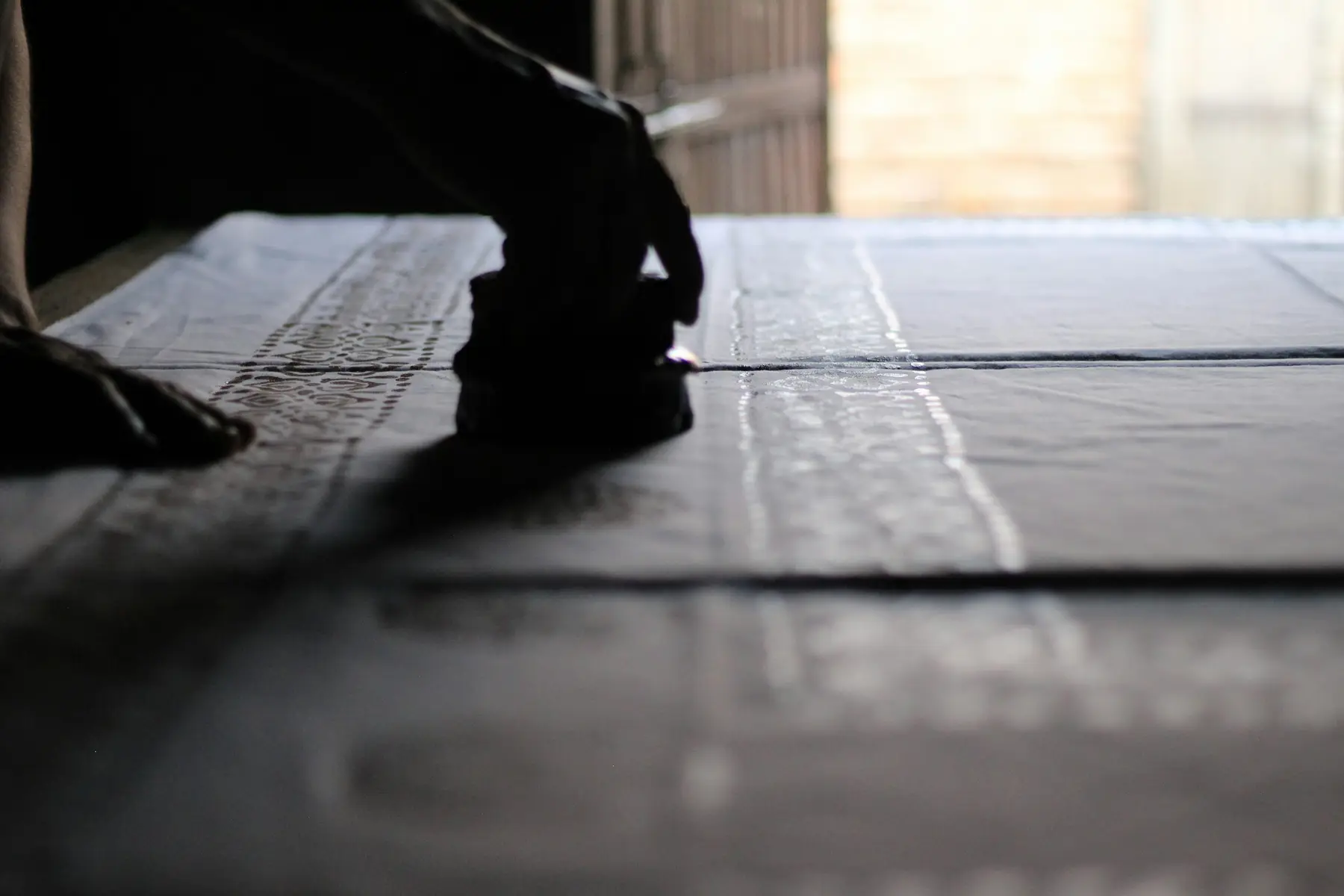 A block-printer's hand at work in a fabric workshop