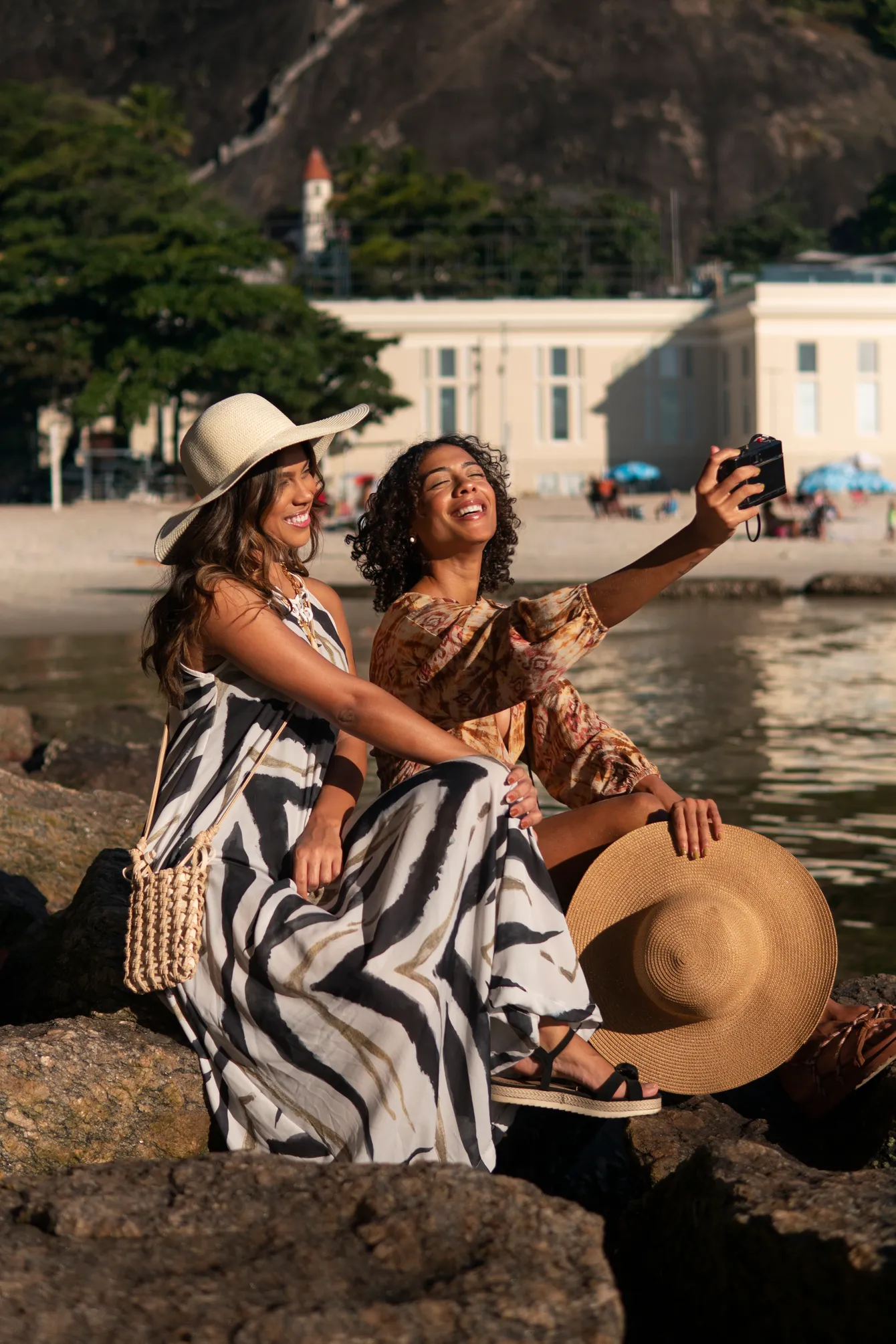Two friends laughing together while taking a photo by the water